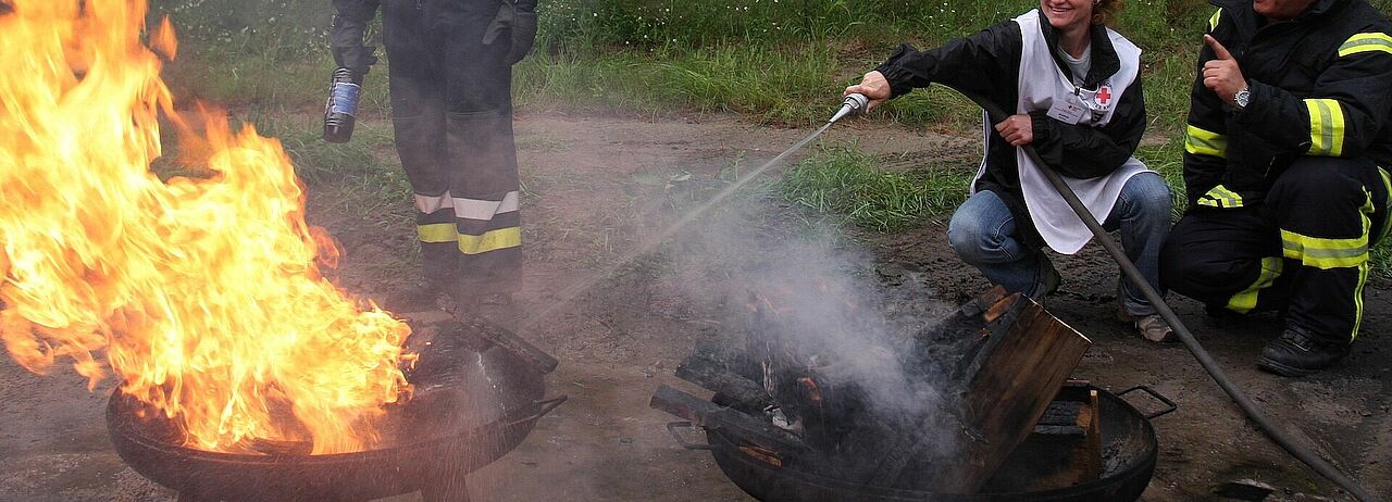 Eine Lehrgangsteilnehmerin löscht unter Anleitung ein Feuer